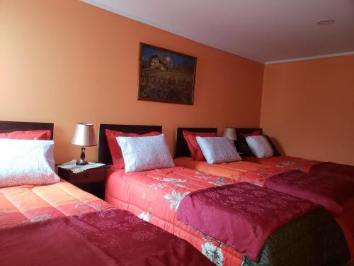 纳塔列斯港Hostal Nataly的橙色墙壁客房的两张床