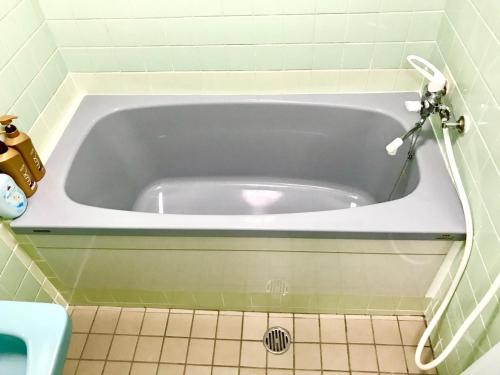 那霸Miyagi Apartment Tomari的带浴缸的浴室,铺有瓷砖地板