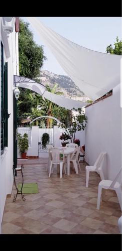 巴勒莫Mondello Home "46 passi"的庭院配有白色的桌椅和白色的遮阳伞。