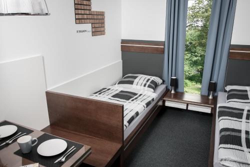 朗斯多夫Triumph Inn Pension的一间卧室配有一张床、一张桌子和一个窗户。