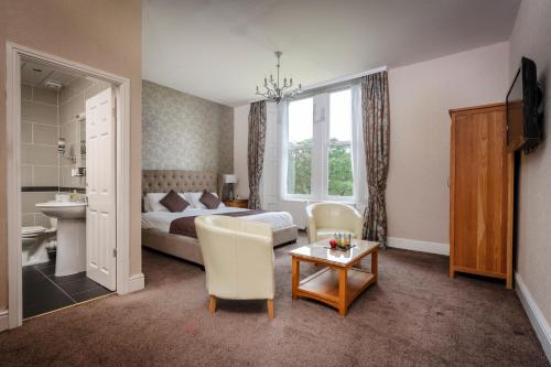伯恩利Burnley North Oaks Hotel and Leisure Club的酒店客房带一张床、一张桌子和椅子