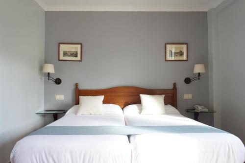 托雷洪-德阿尔多斯Villa Soledad的卧室内的两张床,配有白色的墙壁和灯具