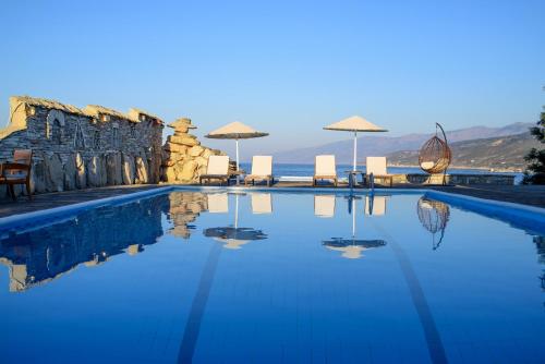 阿梅尼斯蒂斯卡沃斯湾一室公寓酒店的一个带椅子和遮阳伞的游泳池以及大海