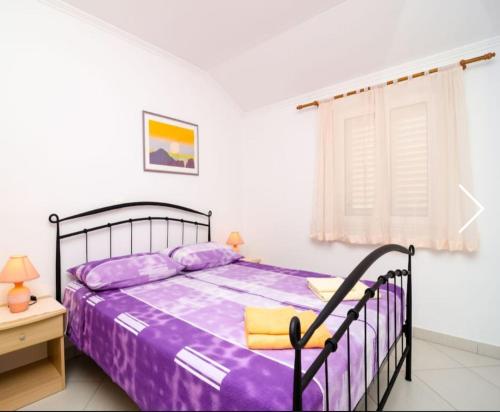 杜布罗夫尼克巴尔塔扎尔公寓式酒店的一间卧室配有一张带紫色床单的床和窗户。