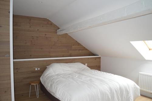 罗什福尔la tourelle d’Achille leontine的卧室设有白色的床和木墙
