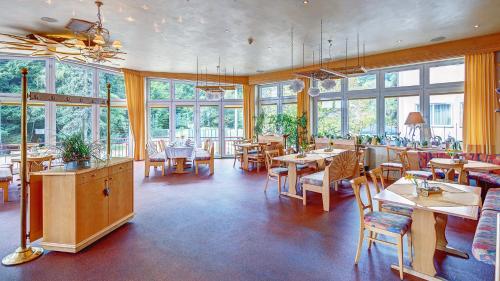 Heimbuchenthal克里斯特尔酒店的餐厅设有桌椅和窗户。