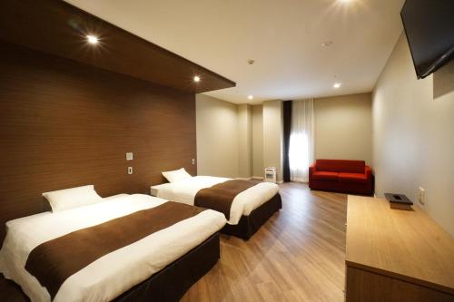 冈山Hotel Abest Grande Okayama的酒店客房带两张床和一张红色沙发