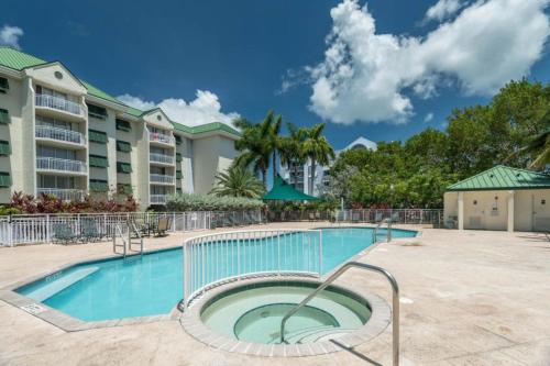 基韦斯特Sunrise Suites Bonaire Suite #210的公寓大楼前方设有桌椅的游泳池