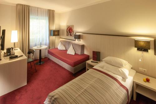 蒙明博格Bergers Airporthotel Memmingen的酒店客房配有两张床和一张书桌