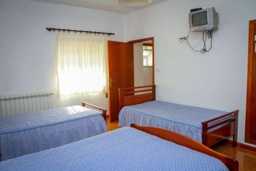 塞亚Hospedaria Santa Cruz的客房设有两张床和一台墙上的电视。