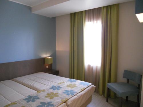 圣港INATEL Porto Santo的卧室配有床、椅子和窗户。
