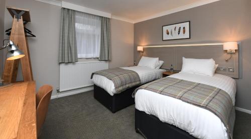 霍伊莱克Green Lodge, Wirral by Marston's Inns的酒店客房设有两张床和窗户。