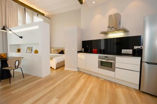 马略卡岛帕尔马L´Aguila Suites - Turismo de Interior的厨房配有白色橱柜、桌子和床。