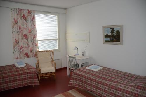 豪基普达斯Lomakoti Onnela的一间卧室设有两张床、一张桌子和一个窗口。