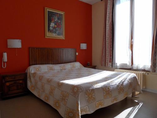 格勒诺布尔Hôtel Victoria的一间卧室配有一张带橙色墙壁和窗户的床。
