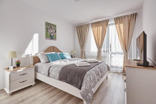 锡纳亚George Apartment Sinaia的白色卧室配有一张带蓝色枕头的大床