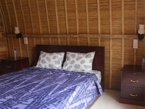 努沙杜瓦Lala Home Stay的一间卧室设有一张床和木墙