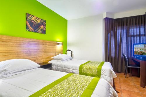 圣何塞克里斯蒂娜套房酒店 的绿墙旅馆客房的两张床