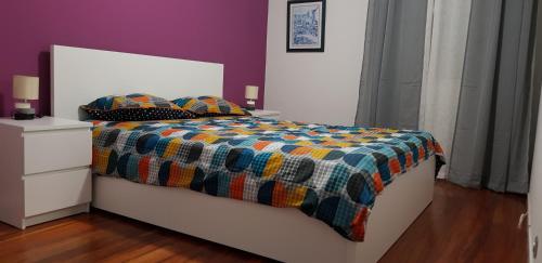 蓬塔德尔加达Varanda do Atlântico的一张带色彩缤纷的被子的床和两个枕头