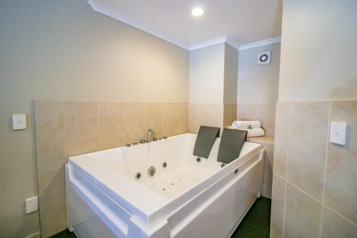 旺格努伊奥提汽车旅馆的浴室设有大型白色浴缸,铺着瓷砖