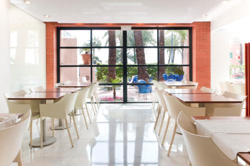 贝尼多姆 帕尔梅拉酒店的餐厅设有桌椅和大窗户。