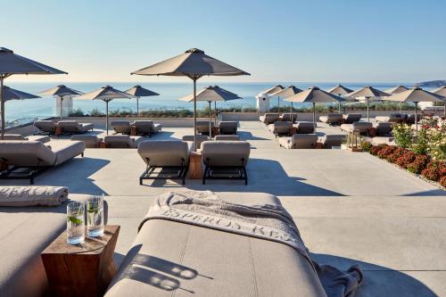 法里拉基Esperos Village Blue & Spa - Adults Only的海滩上的一排躺椅和遮阳伞