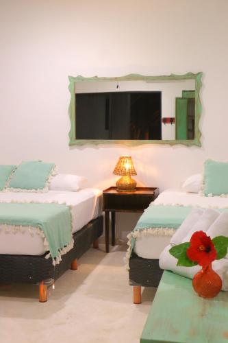 图卢姆波萨达蓬彼德拉海滩酒店的一间设有三张床的客房,墙上设有一面镜子