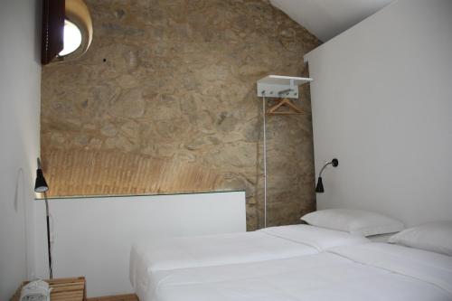 索布拉尔德蒙特阿格拉苏Casa de Campo Moinhos da Gozundeira的石墙客房内的2张白色床