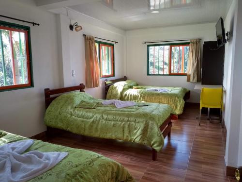 AguadasParaíso Tropical的带三张床和黄色椅子的房间