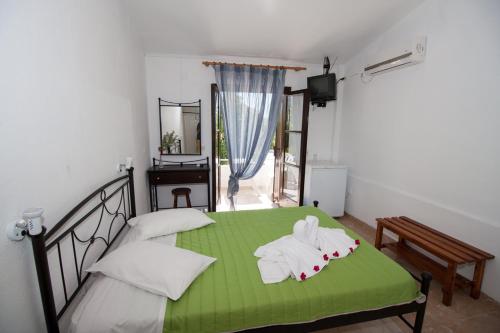 里科索翁凯法利尼亚海滩简易别墅酒店的一间卧室配有绿床和毛巾