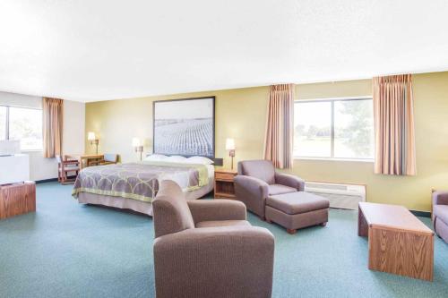 厄尔温Super 8 by Wyndham Oelwein的大型酒店客房,配有床和椅子