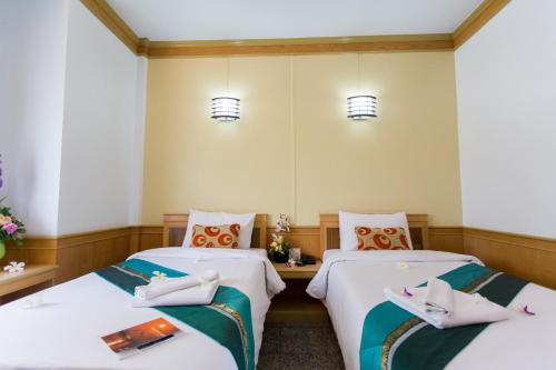 合艾Boom Forest Hotel的配有白色床单的酒店客房内的两张床