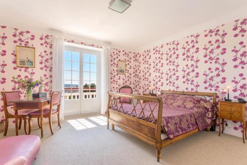 圣让-德吕兹莱斯戈兰斯酒店的卧室配有粉红色的花卉壁纸、一张床和一张桌子