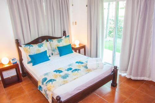 蓬塔卡纳Cocotal Bavaro Apartments的一间卧室配有一张带蓝色枕头的床和一扇窗户。