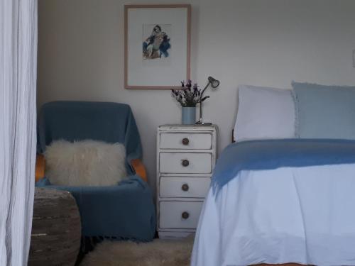 玛普瓦Mapua Studio Quality Accommodation的一间卧室配有一张床、一把椅子和一个梳妆台