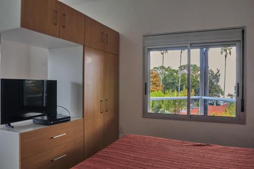 亚特兰蒂斯达Paradise Complejo Turístico的一间卧室设有一张床、一台电视和一个窗口。