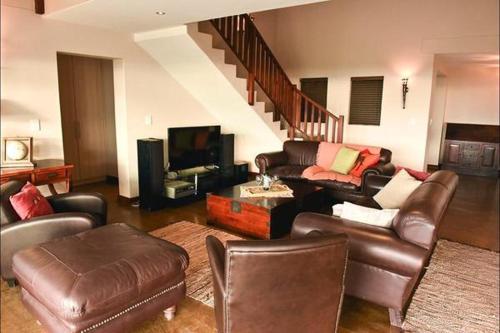 DwarskersbosHemel op Aarde Villa的客厅配有皮革家具和楼梯
