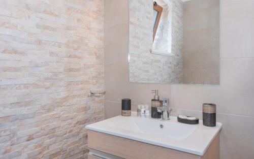 卡拉马孔Green Stone Villas Apartments的一间带白色水槽和砖墙的浴室