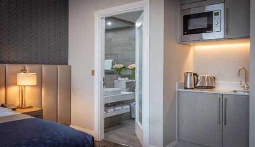 利默里克Castletroy Park Hotel Suites的酒店客房设有带床和水槽的浴室