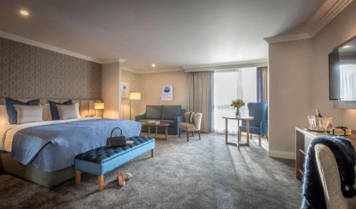 利默里克Castletroy Park Hotel Suites的酒店客房配有一张床、一张沙发和椅子。