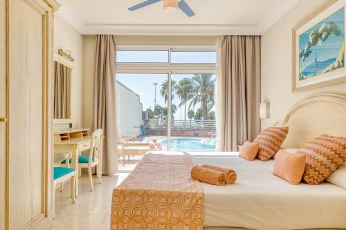 阿马多雷斯Holiday Club Playa Amadores的一间卧室配有一张床,享有游泳池的景色