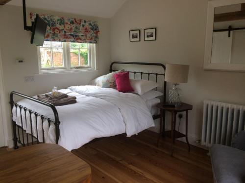 Gilling EastThe Parcel Shed的一间卧室配有带白色床单和粉红色枕头的床。