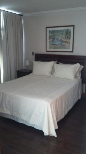 圣地亚哥Austral Rentahome Américo Vespucio Norte的卧室内的一张带白色床单和枕头的床