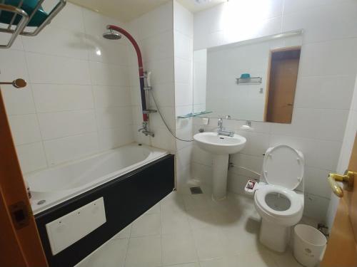大邱New Grand Hotel的浴室配有盥洗盆、卫生间和浴缸。