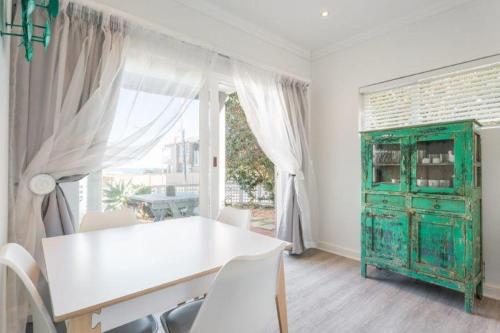 维德尼斯瑞克妮海滨别墅酒店的一间设有白色桌子和绿色橱柜的用餐室