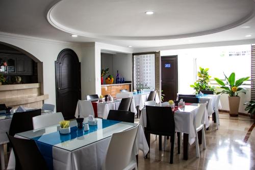 卡利Hotel Ingenio Reina Isabel的一间设有白色桌椅的用餐室