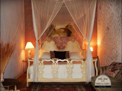 埃尔富埃尔特Hotel Torres Del Fuerte的卧室配有带窗帘的白色天蓬床