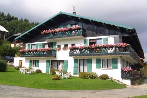 莱热阿尔卑斯花卉小屋酒店的阳台和桌子上鲜花的房子