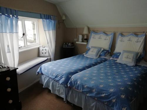 波尔佩罗The House on the Props的一间卧室配有一张带蓝色床单的床和一扇窗户。