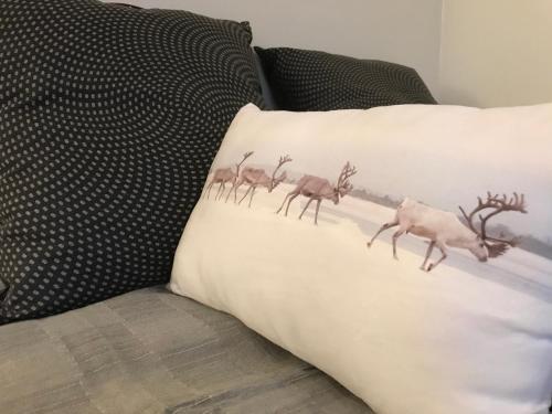 罗瓦涅米Arctic Sofia Riverstudio的沙发上的一个枕头,上面有一群鹿